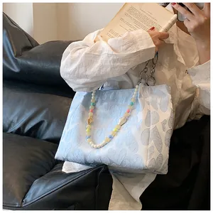Detailed view of a sweet blue tote bag featuring a colorful beaded strap and heart patterns