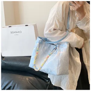Detailed view of light blue embossed tote bag with colorful beaded handle accessory