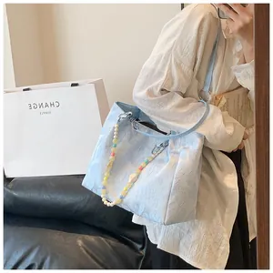 Detail of light blue jacquard heart pattern tote bag with colorful beaded shoulder strap