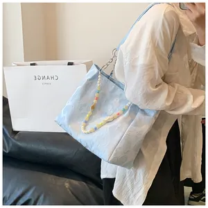 Detailed view of a light blue patterned tote bag with colorful beaded chain handle