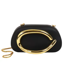 Detail view of matte black evening clutch bag with gold metallic hardware and chain