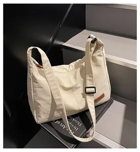Detailed view of cream canvas messenger bag styled on a book for a minimalist aesthetic