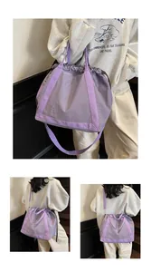 Paarse nylon crossbodytas met trekkoord, getoond in de hand en over de schouder op model