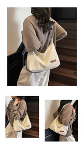 Detail view of a large cream canvas crossbody bag worn by a model in a lifestyle setting