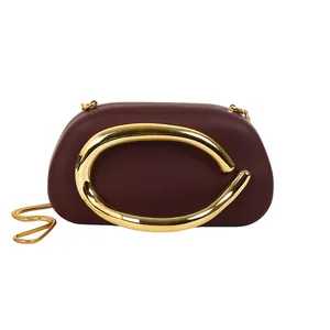 Detailed view of burgundy evening clutch with golden C-shaped metallic hardware decoration