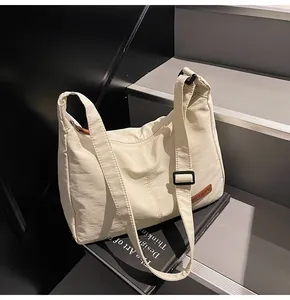 Large cream minimalist canvas messenger bag shown on stairs as a lifestyle detail