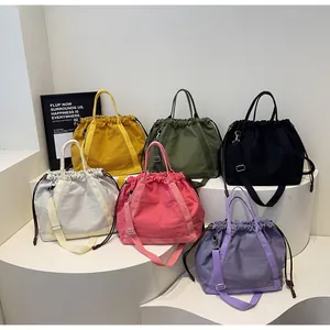 Collectie kleurrijke nylon emmertassen met trekkoord op moderne witte displaystandaards
