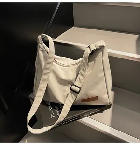 Close-up detail of a large beige canvas crossbody messenger bag for casual daily use