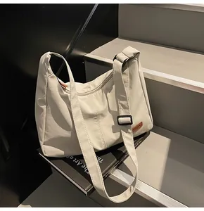 Close-up view of a minimalist large grey canvas messenger bag placed on a book prop