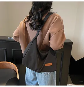 Detailed back view of a large black canvas messenger bag worn for a casual daily look.