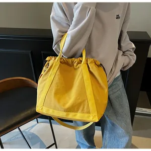 Gele nylon tas met trekkoord gedragen door een model in een mooie casual omgeving