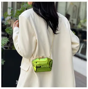 Trendy lime green acrylic clutch bag with gold chain shown on a white blazer model