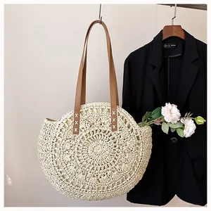Detail of a round woven straw beach bag with intricate hollow floral patterns.