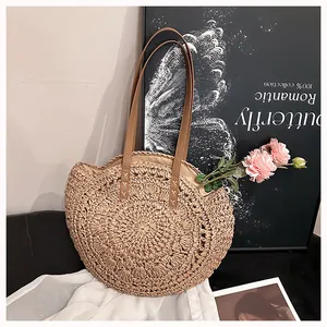Detail showing the natural hand-woven texture of this elegant round straw shoulder bag.