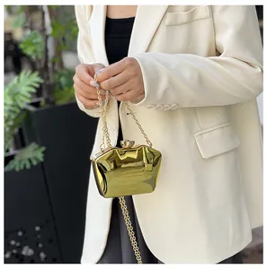 Detailed view of gold metallic acrylic clutch bag featuring a jewel clasp and chain