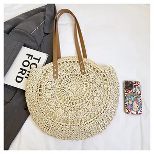 Detailed overhead view of a round hollow-out flower straw bag with leather straps.