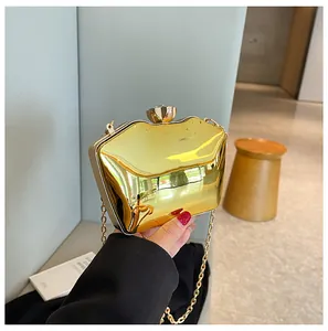 Detail of a gold metallic evening clutch bag with flower clasp and chain strap.