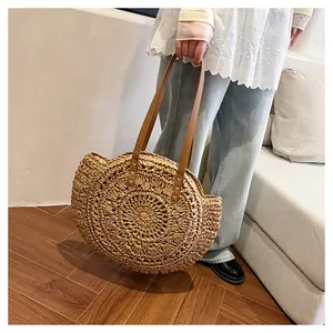 Lifestyle detail view of a round openwork floral straw shoulder bag for beach trips