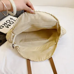 Detailed interior view of a round beige woven straw beach bag with zipper pockets