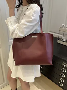 Élégant sac cabas bordeaux en similicuir de grande capacité porté par une femme au quotidien