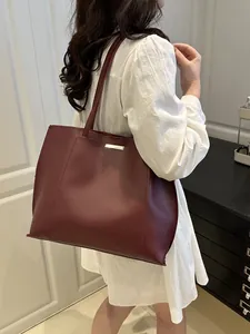 Vue détaillée d'un grand sac cabas en cuir souple bordeaux porté à l'épaule