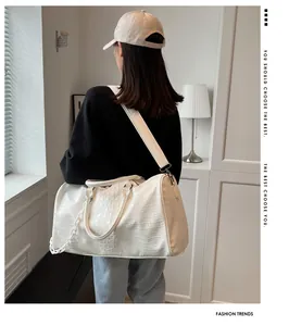 Detailed back view of a white crocodile pattern large travel bag carried by a fashion model