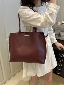 Mannequin en robe blanche portant un grand cabas vintage en cuir souple bordeaux à l'épaule