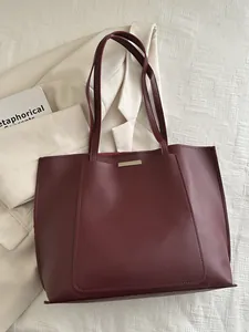Vue détaillée d'un grand sac cabas en cuir bordeaux posé sur un blazer beige chic