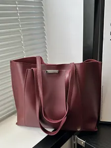 Détail latéral du sac cabas en cuir souple bordeaux avec barre métallique argentée élégante