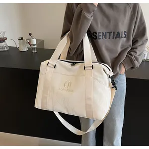 Borsa da viaggio color crema con finitura testurizzata indossata da una modella in un bar