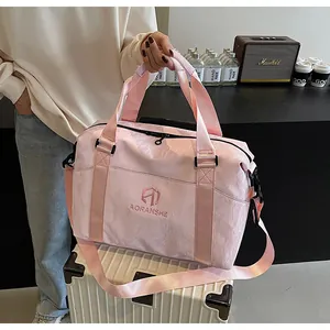Borsa da viaggio rosa leggera da donna tenuta a mano sopra una valigia bianca lucida