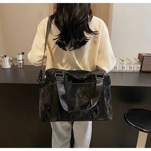 Vista posteriore di una donna con una grande borsa da viaggio nera con trama stropicciata