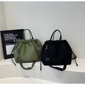 Detail van twee minimalistische nylon tassen met trekkoord in groen en zwart op wit.
