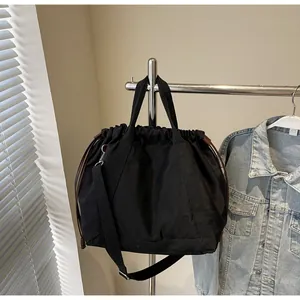 Zwarte nylon bucket bag met trekkoord hangend aan een metalen rek in een setting