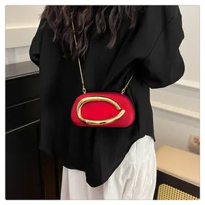 Elegant red evening clutch bag featuring a large gold metal ring accent shown on model