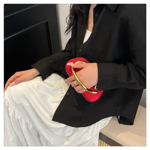 Stylish red evening clutch bag with a chunky gold metal handle held by a fashion model