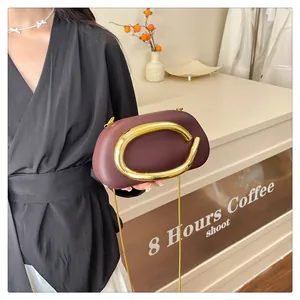 Elegant burgundy evening clutch bag with a unique gold oval handle held by a model.