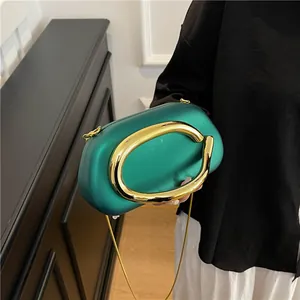 Elegant emerald green evening clutch bag with unique gold C-shaped handle and chain strap.
