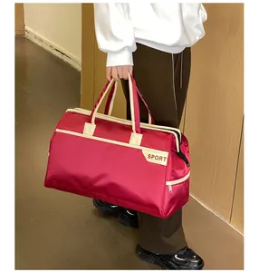 Modell trägt eine große weinrote wasserfeste Reisetasche in einem Innenraum