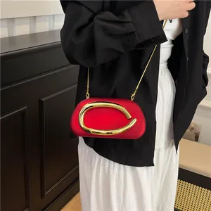 Elegant red evening bag with bold gold C-shaped clasp and delicate chain strap