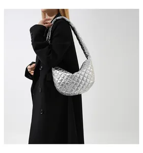 Side view of a metallic silver quilted shoulder bag carried by a model in a black coat