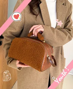 Detailed view of brown fuzzy cosmetic bag with leather handle held by model