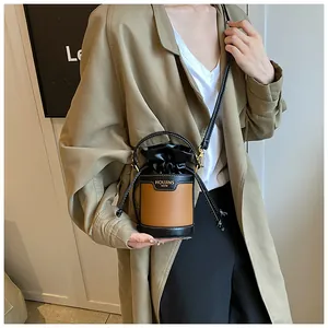 Modern two-tone brown and black drawstring bucket bag shown as a crossbody detail