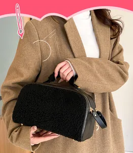 Detail view of a black faux fur cosmetic bag carried by a model in a tan coat