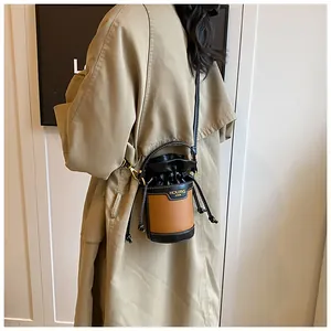 Detailed view of a minimalist contrast color cylinder bucket bag featuring a drawstring closure