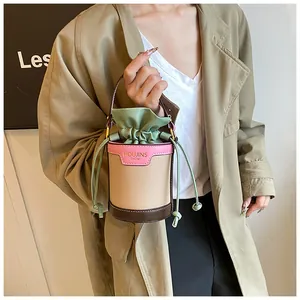 Detailed close-up of a stylish color-block bucket bag featuring a green drawstring closure