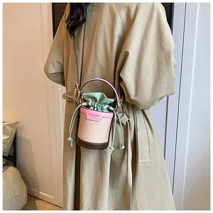 Fashionable color-block cylindrical bucket bag with drawstring closure shown on model