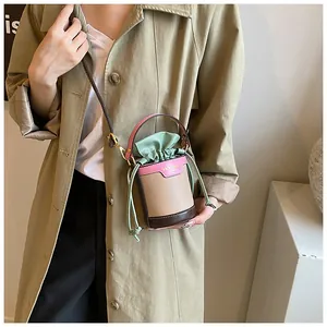 Detail view of a stylish color block drawstring bucket bag worn with a trench coat