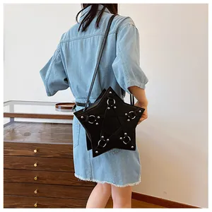 Detail view of a black pentagram star-shaped crossbody bag worn by a model in a denim dress.