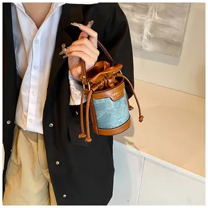 Close-up detail of a denim and leather patchwork bucket bag with drawstring closure